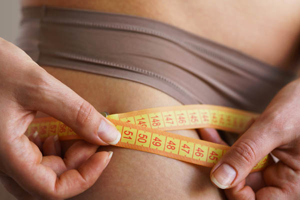 Woman measures her hips with a tape