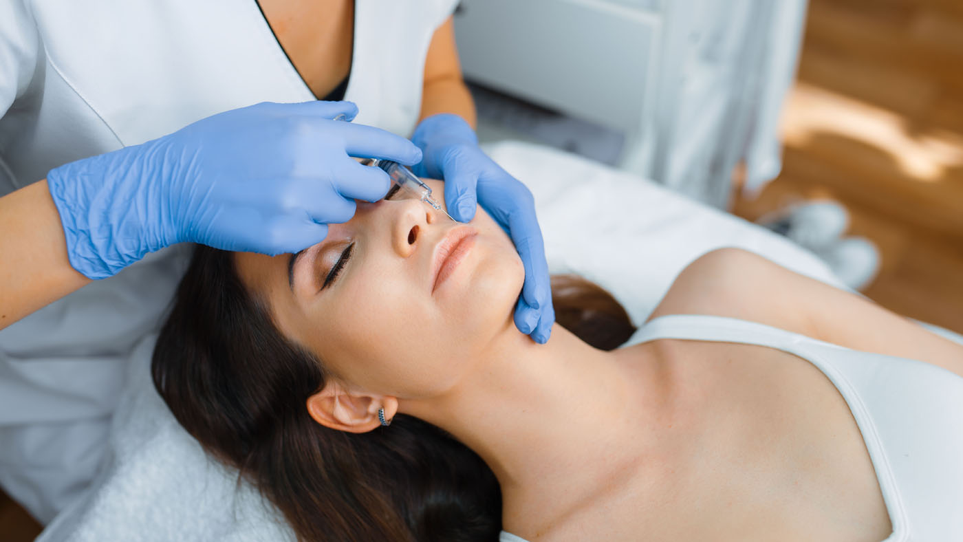 Cosmetician gives face botox injections to patient