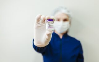 nurse practitioner in a mask and gloves holding up a botox bottle